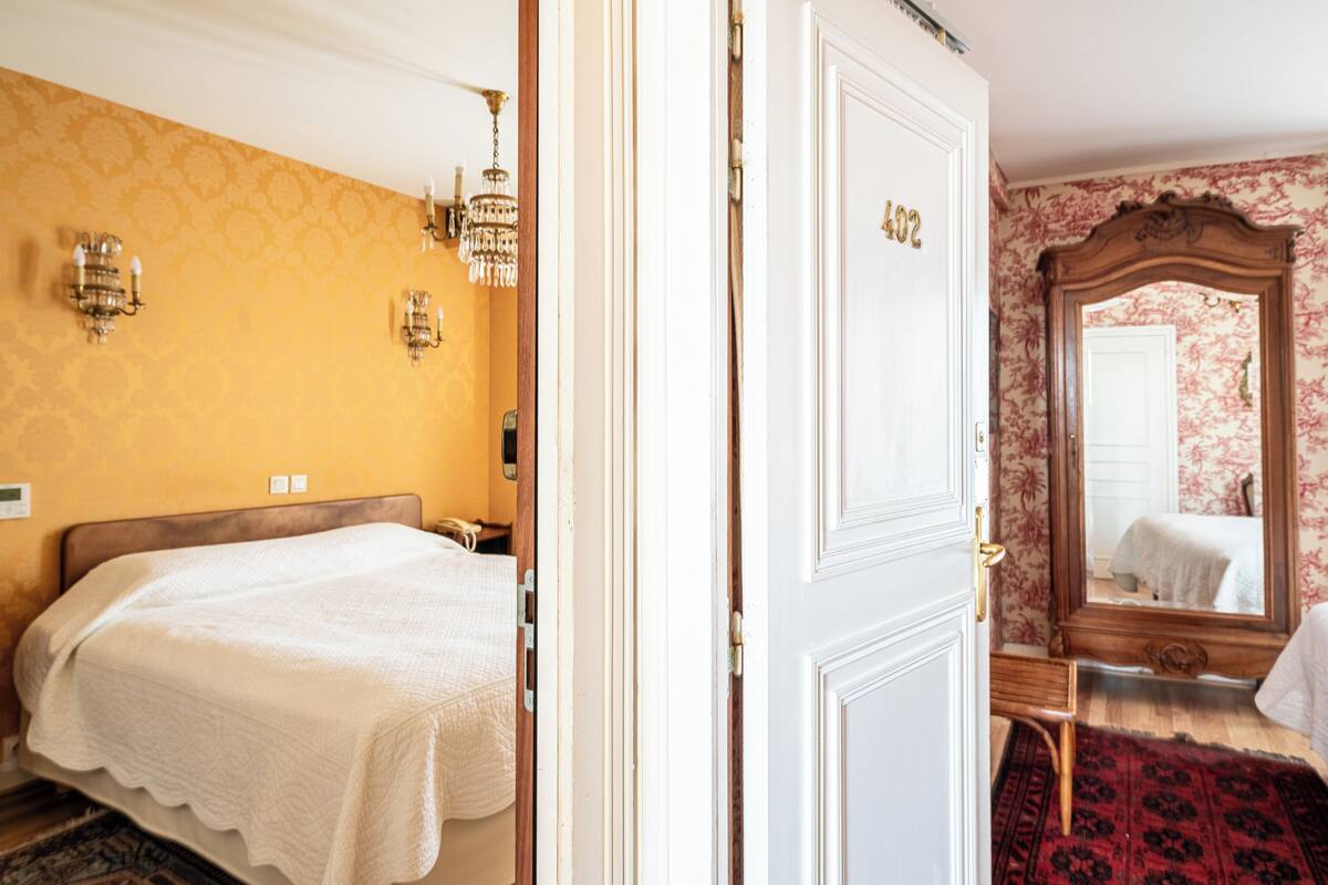 Ein Hotelzimmer mit einem Bett, einer Tür mit einer Nummer, einem Spiegel und einer Wand mit Muster.