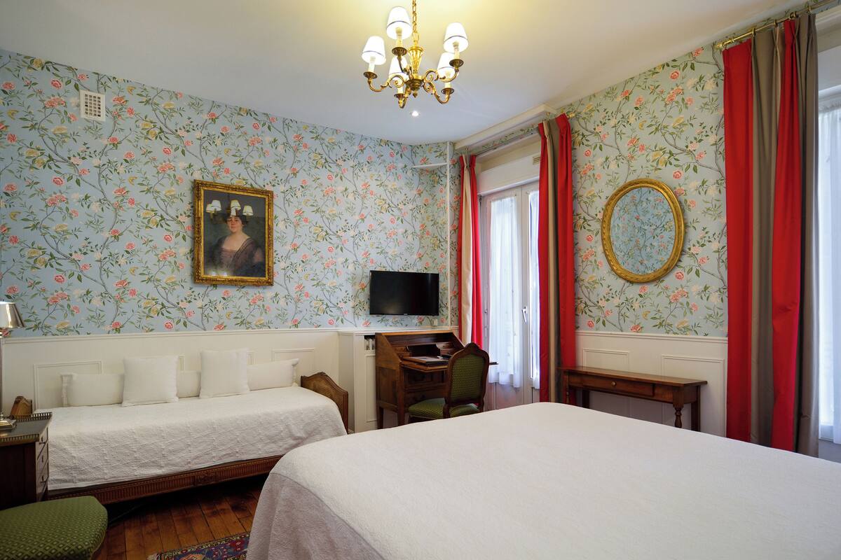 Ein Schlafzimmer mit zwei Betten, einem Schreibtisch, einem Stuhl, einem Fernseher und einem Spiegel.