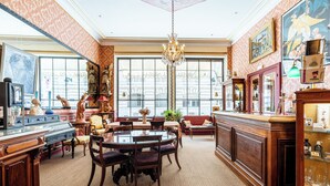 Een ruime kamer met een grote ronde tafel, houten meubels en een barhoek.