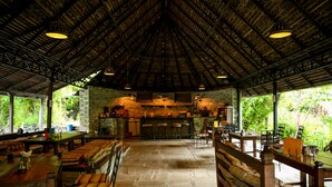 A spacious indoor area with wooden benches and tables, a stone floor, and a high ceiling with exposed beams. - The Last Resort (Listikot)