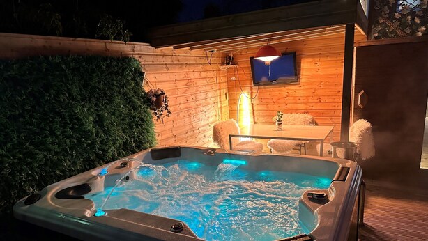 Un jacuzzi con cubierta de madera y un televisor fijado a la pared.