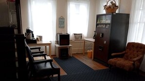 A living room with a sofa, a chair, a television, a refrigerator, and a table. - Surf Villa Hotel (Ocean City)