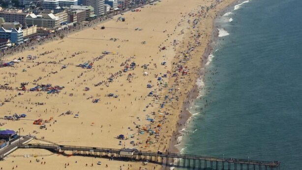 A beach with a pier extending into the water, surrounded by buildings. - Surf Villa Hotel (Ocean City)