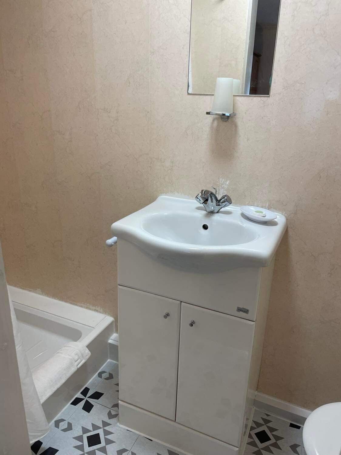 A bathroom with a white sink, a mirror, and a toilet.