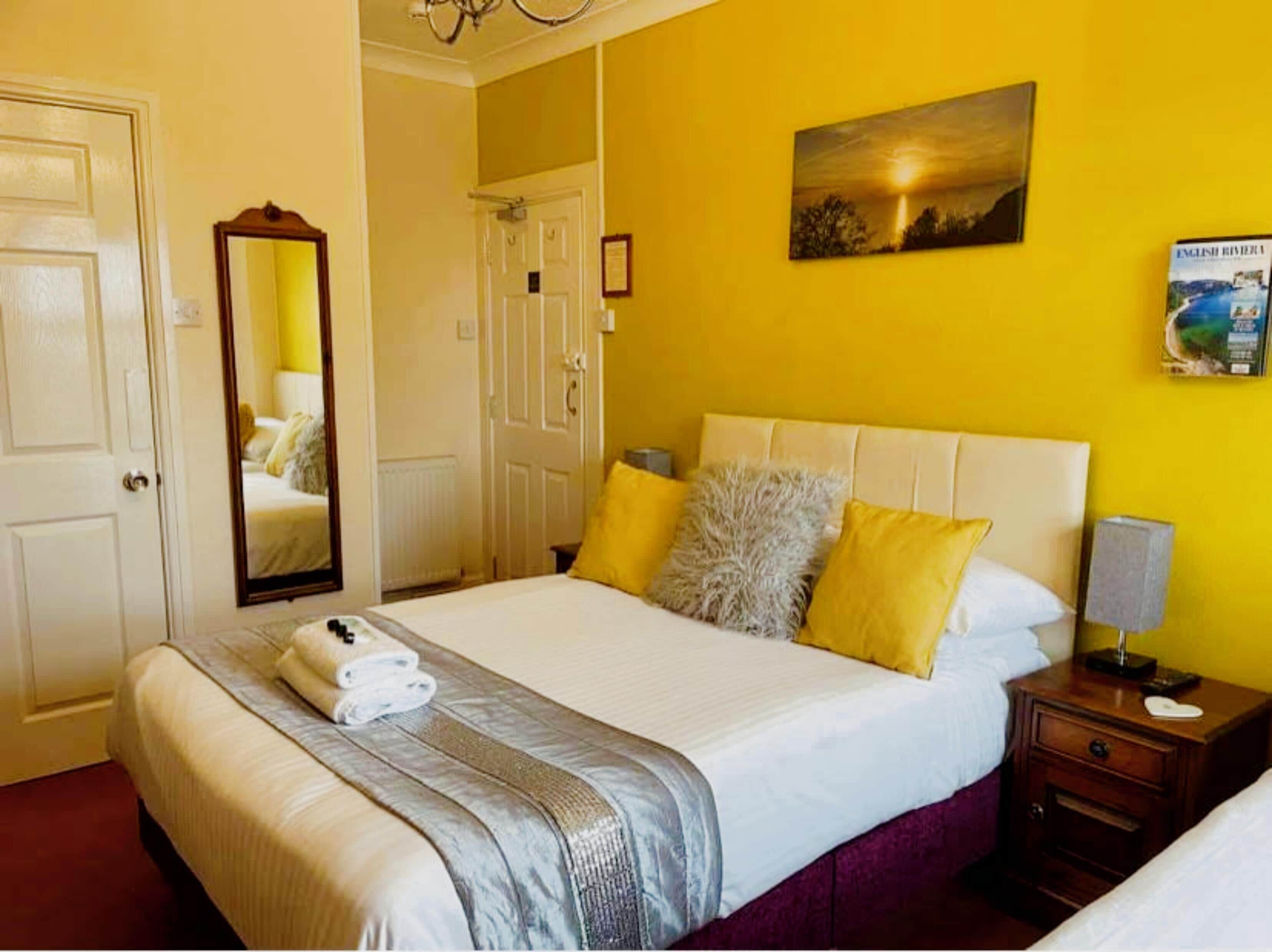 Una habitación de hotel con una cama grande, una lámpara de noche, una mesita de noche y un cuadro en la pared.