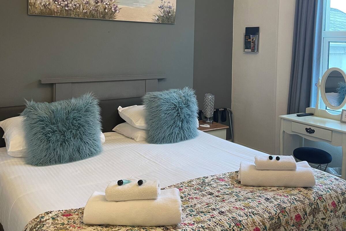 Een hotelkamer met een bed, een schilderij, een bureau en een raam.