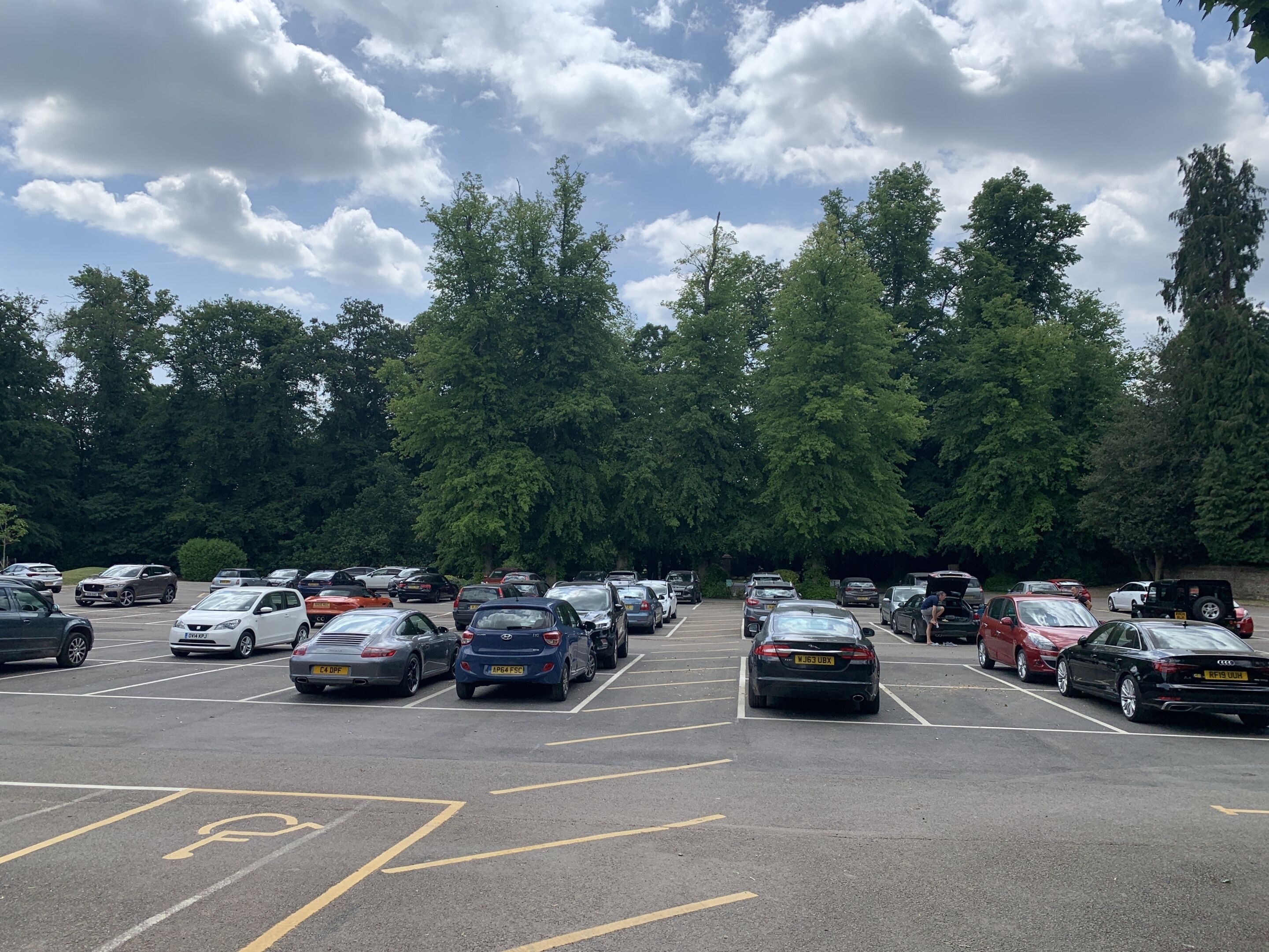 A parking lot with multiple cars and trees in the background.