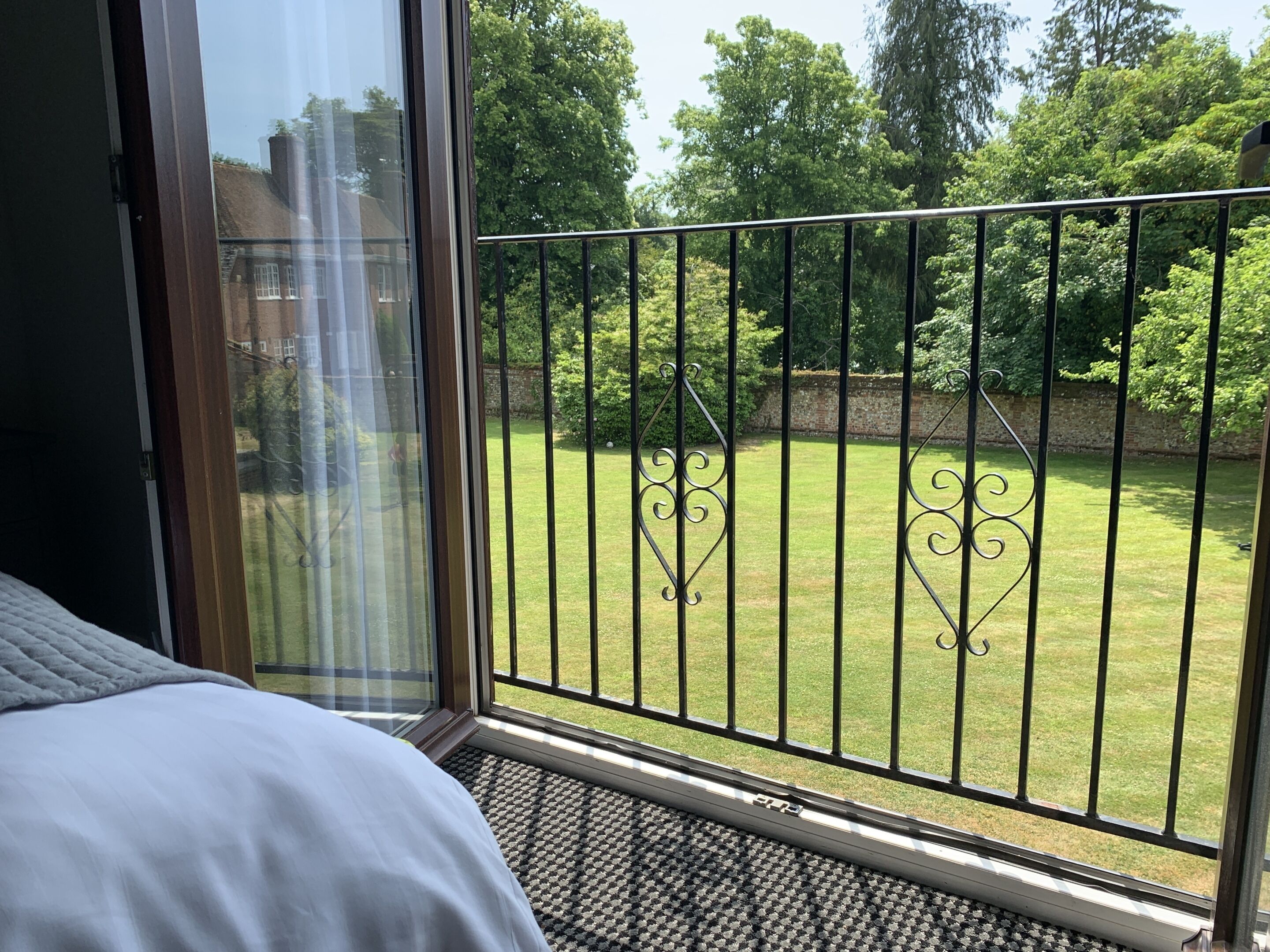 A balcony with a view of a well-maintained lawn and trees.