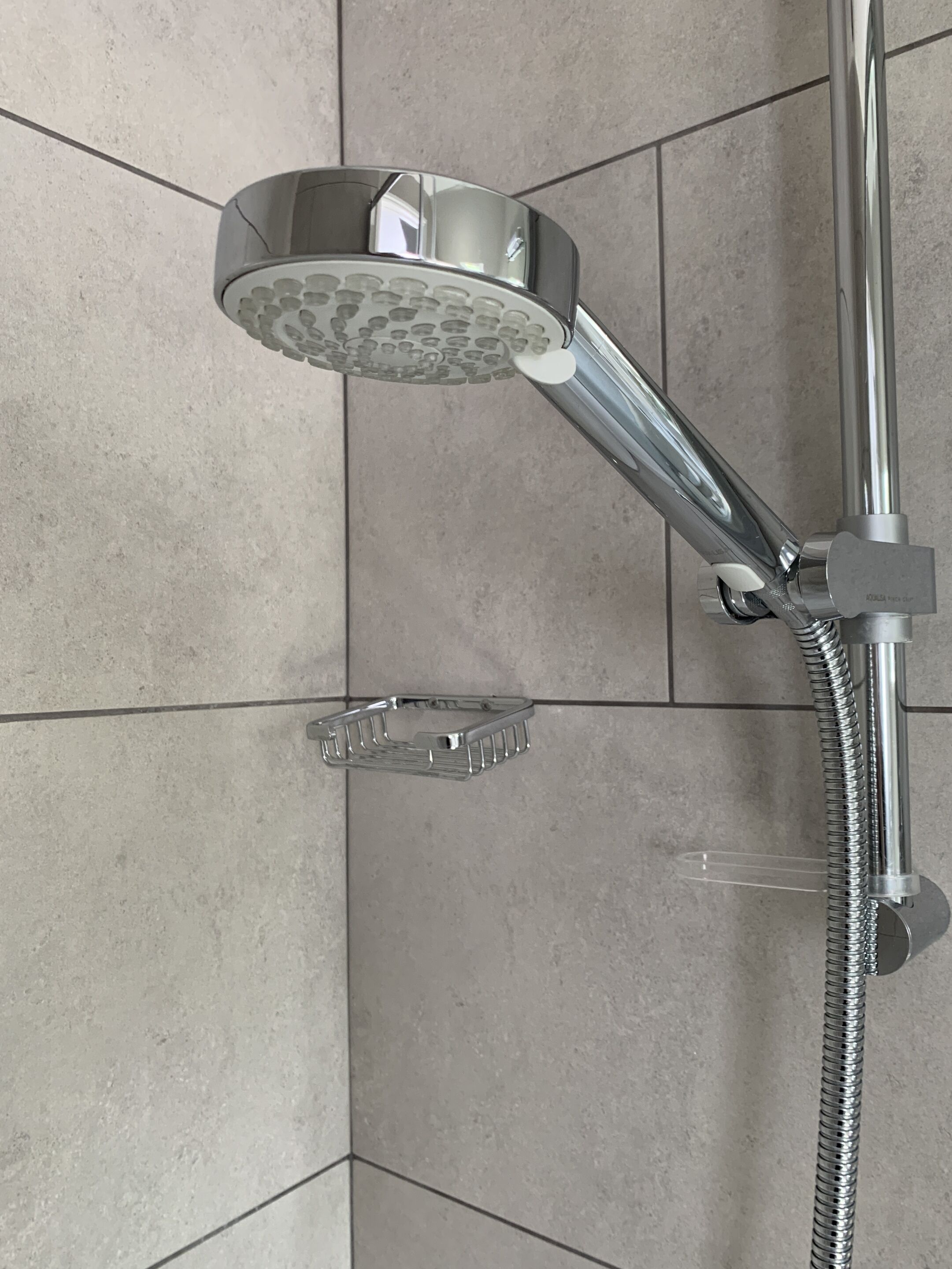 A chrome showerhead with a flexible hose, mounted on a tiled wall.