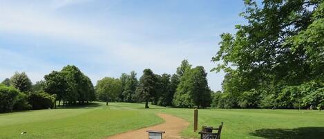 A park with a dirt path, a wooden bench, and a signpost.