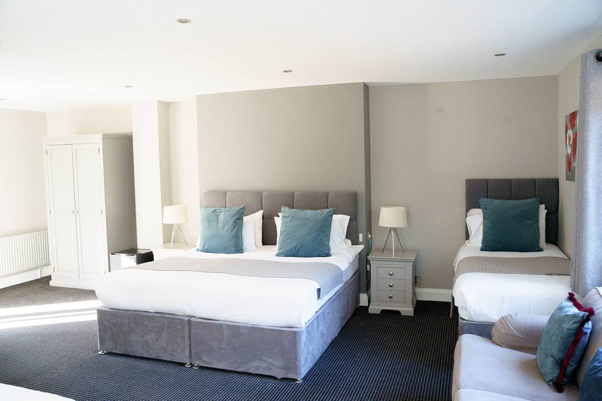 Una habitación de hotel con dos camas, un armario y una mesita de noche con lámparas.