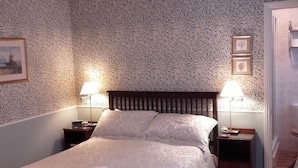 A neatly made bed with a patterned bedspread, two bedside lamps, and framed pictures on the wall.