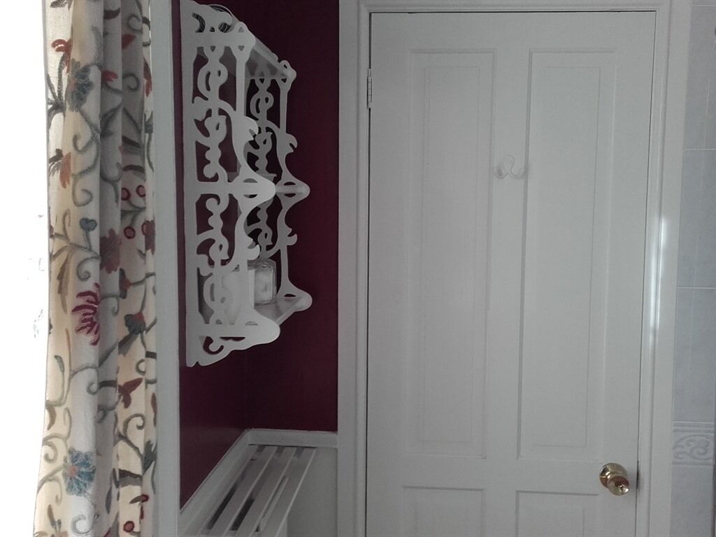 A white door with a decorative metal piece above it and a patterned curtain to the left.