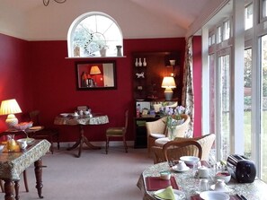 A dining area with a red wall, a large window, and a cozy seating arrangement. - Beaufort Lodge (Norwich)