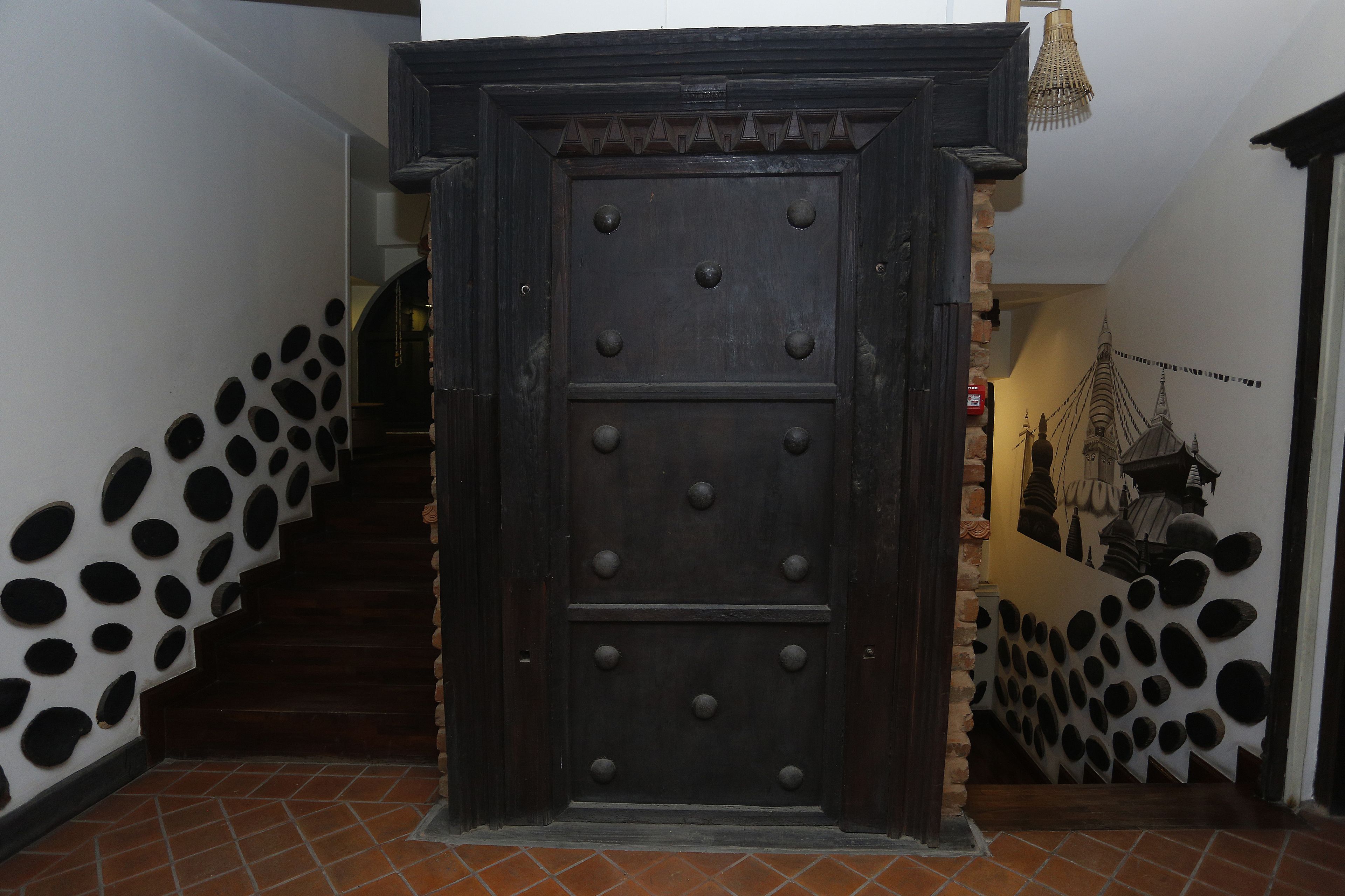 A staircase with a dark wooden door at the top, flanked by walls with circular cutouts.