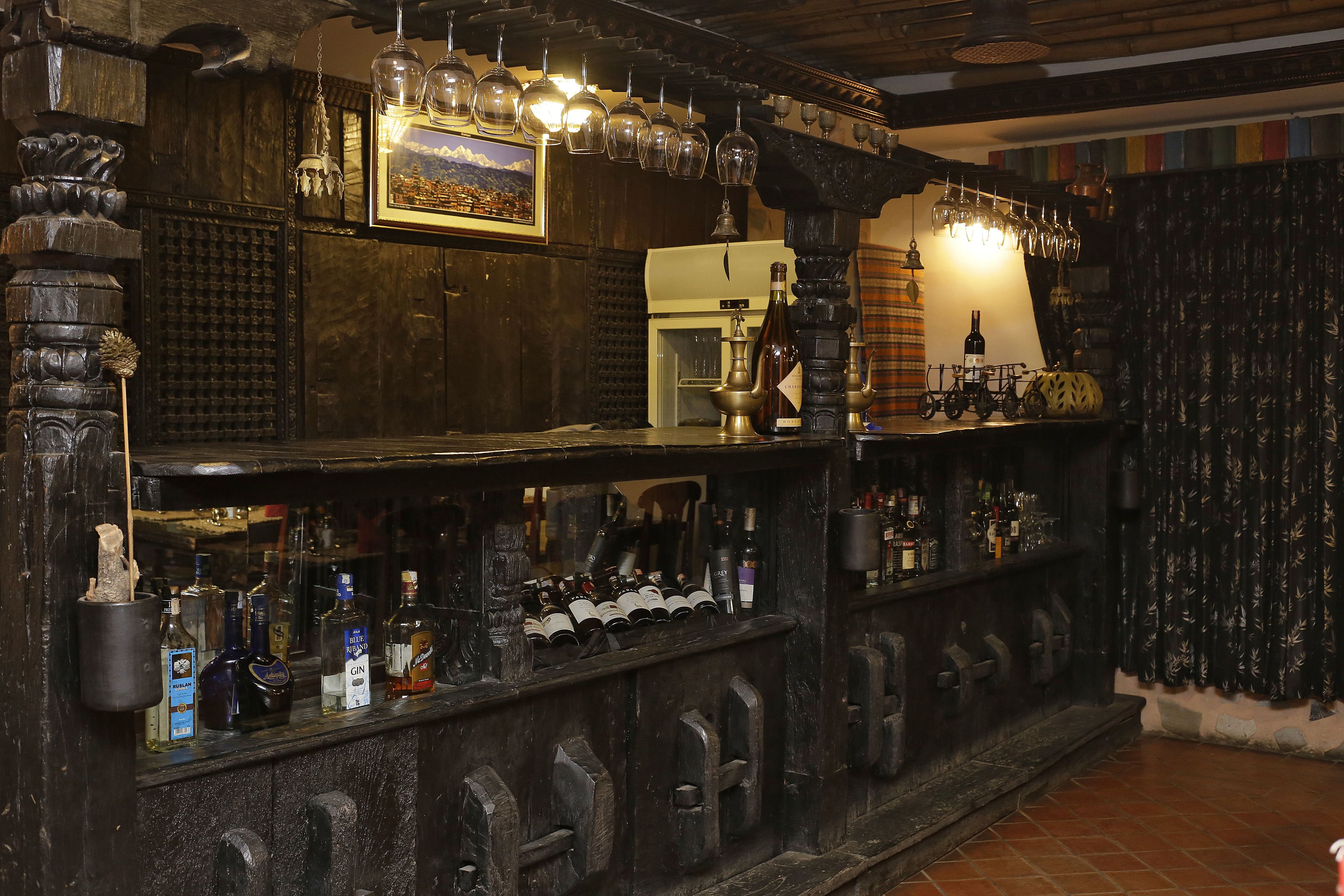 A bar area with wooden decor, bottles, glasses, and a vintage bicycle.