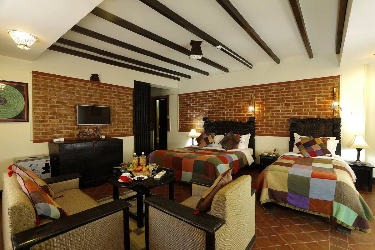A hotel room with two beds, a TV, a desk, and a dining table.