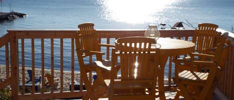 Une terrasse en bois avec une table et des chaises donnant sur une étendue d’eau.
