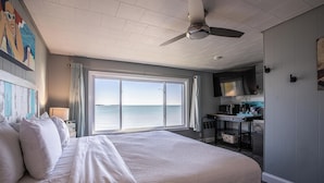 Une chambre d’hôtel avec un grand lit, un ventilateur de plafond, un coin cuisine et une vue sur la mer.
