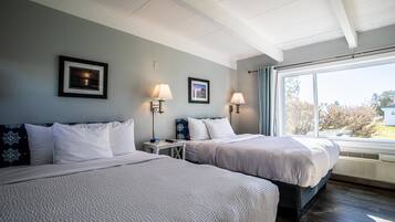 A hotel room with two beds, a large window, and a view of the outside.