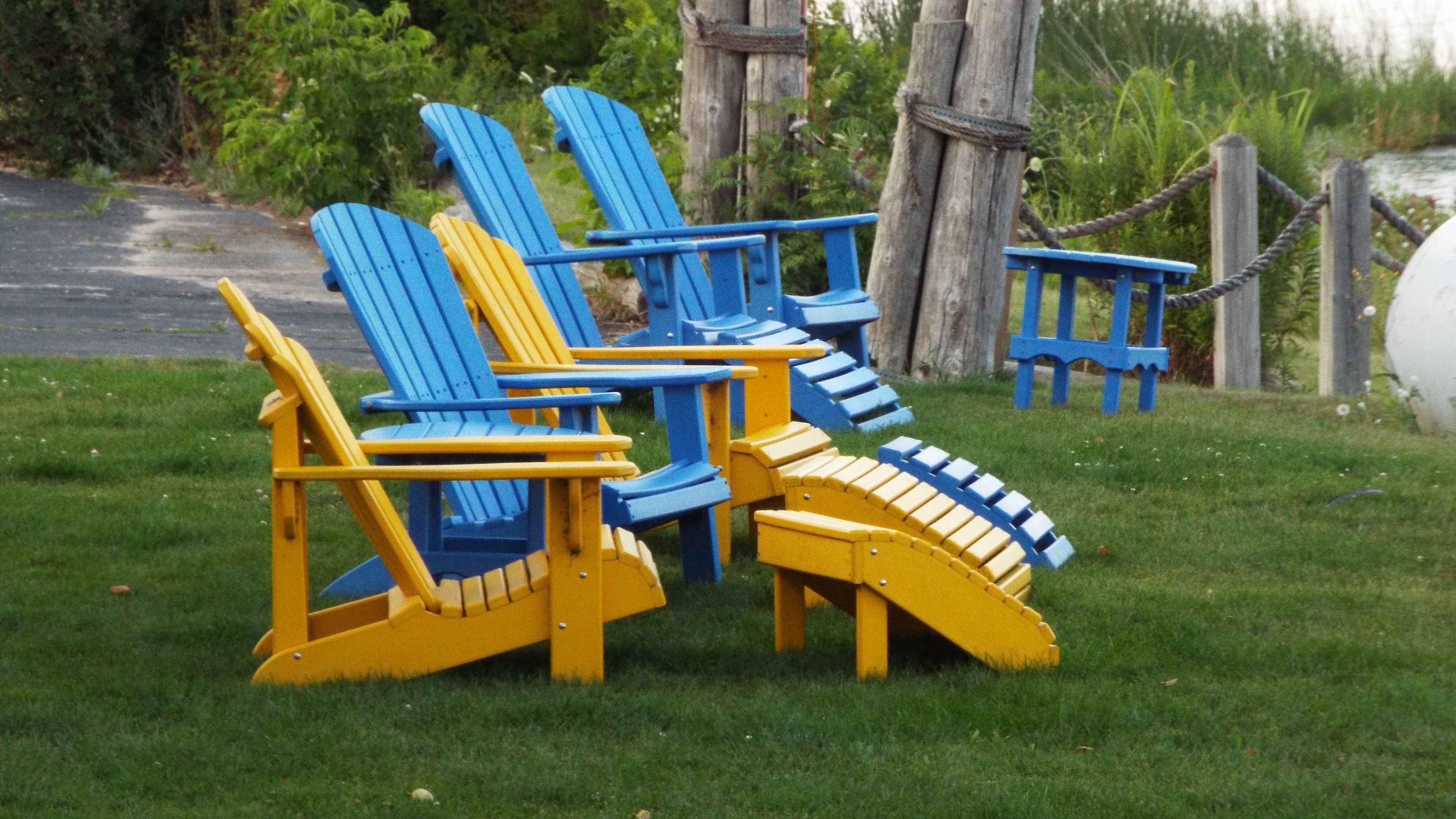 Mobiliario exterior con sillas Adirondack azules y amarillas.