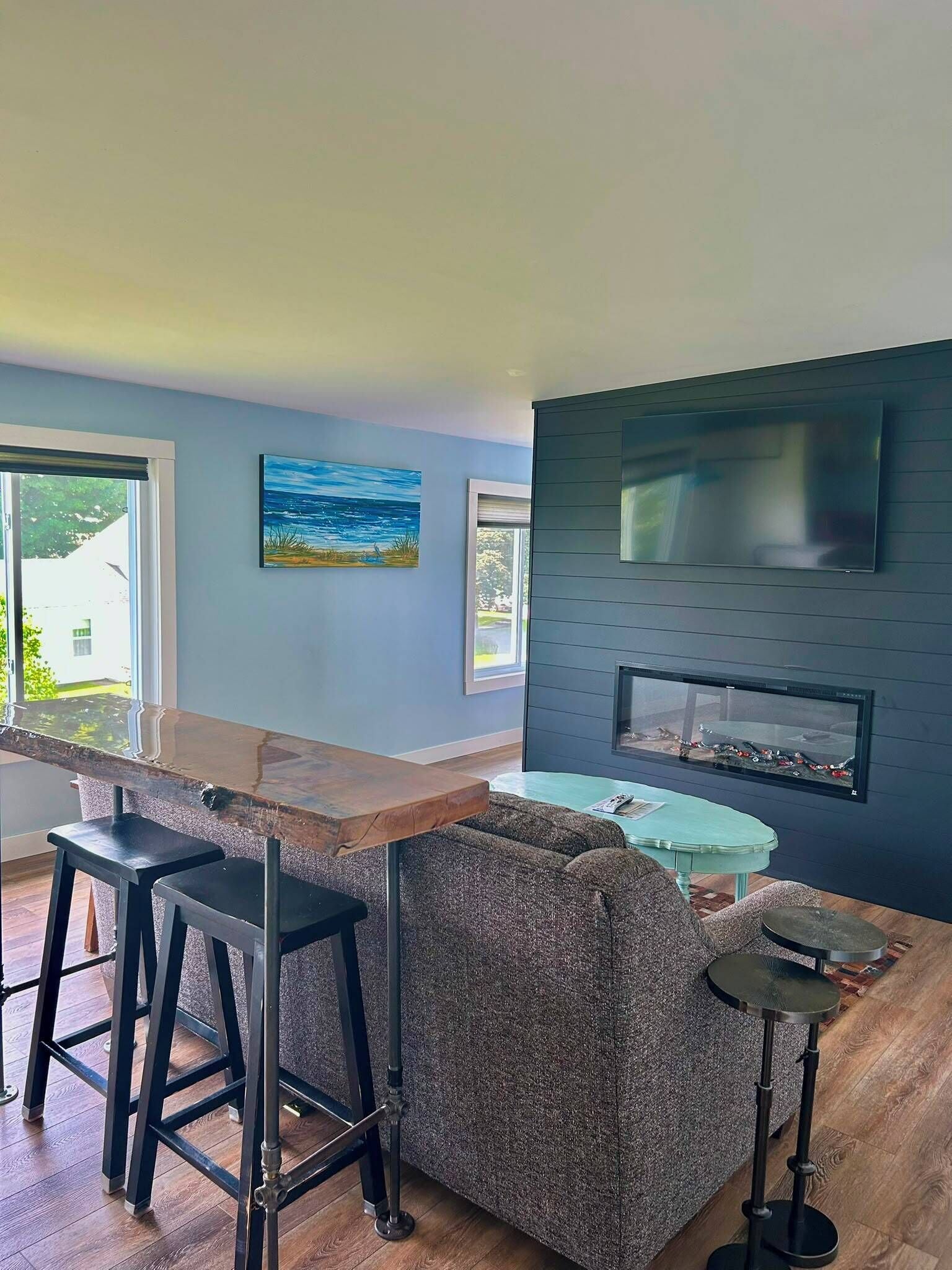 A modern kitchen with a bar area, a large window, and a flat-screen TV mounted on the wall.