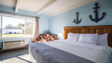 A bedroom with a large bed, a wooden headboard, a window with curtains, and two anchors on the wall.
