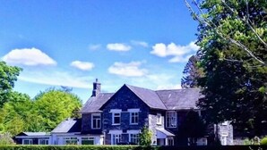 A large stone house with multiple windows and a well-maintained lawn. - Bluebird Lodge and Waterhead Apartment (Coniston)