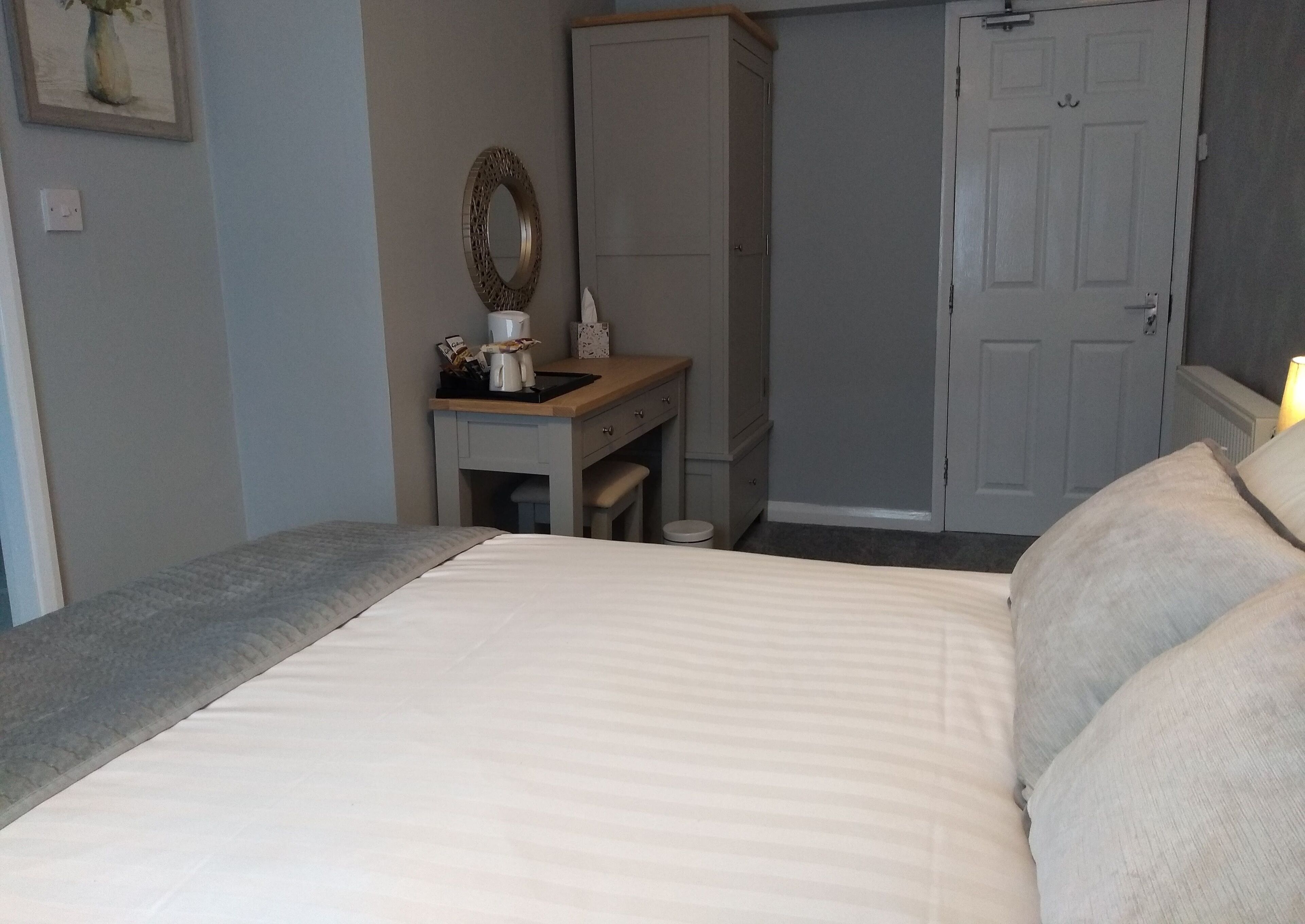 Une chambre à coucher avec un lit, une table de chevet avec une lampe, une armoire et une porte.
