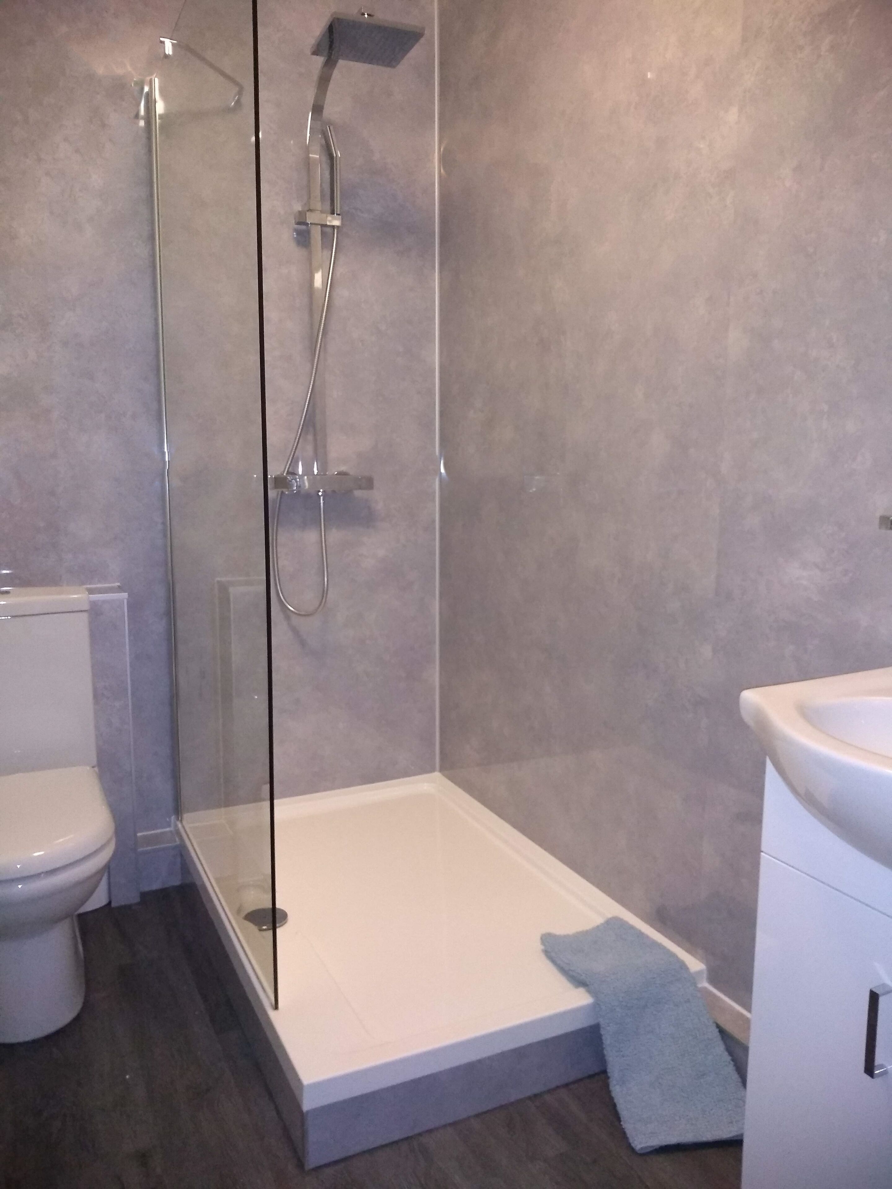 A bathroom with a glass-enclosed shower, a toilet, and a sink.