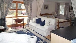Un dormitorio con cama, una silla, un escritorio y una ventana.