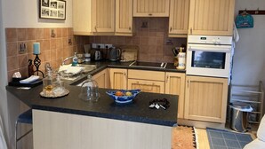 Una cocina con armarios de madera, una encimera negra, un fregadero, una estufa y un salpicadero de azulejos.