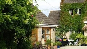 Un edificio de estilo europeo tradicional, con fachada de piedra, muros cubiertos de hiedra y tejado de paja.