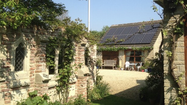 Un patio con un edificio de piedra, una bandera y un techo con paneles solares.