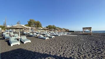 On the beach, black sand, sun loungers, beach umbrellas