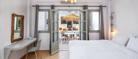 Habitación de hotel con cama, escritorio, silla y vista al área de piscina al aire libre.