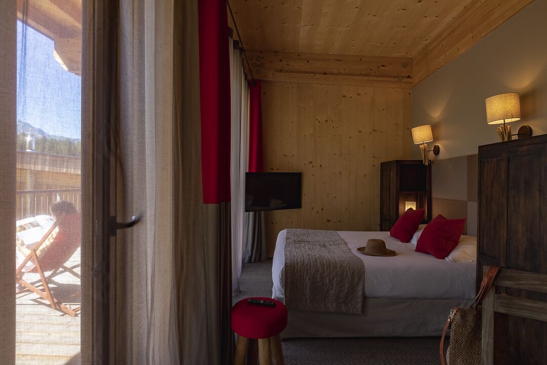 A hotel room with a bed, a television, and a view of the outdoors.