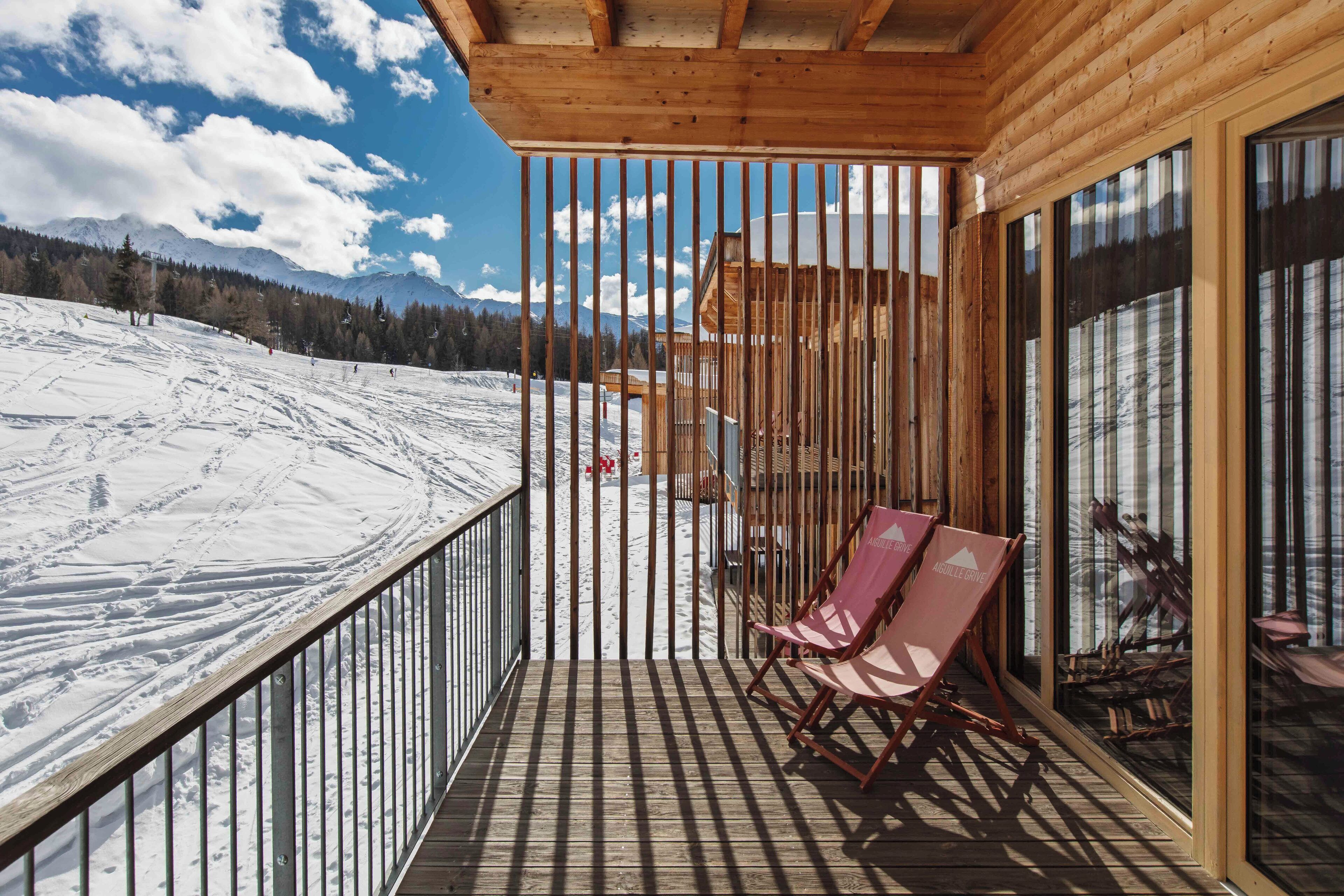 A wooden balcony with a view of a snowy mountain slope.