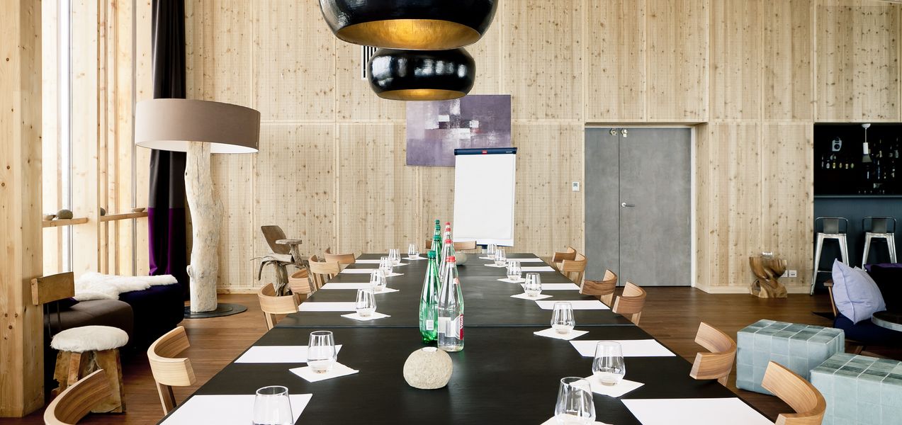 A conference room with a long table, chairs, a whiteboard, and a bar area with stools.