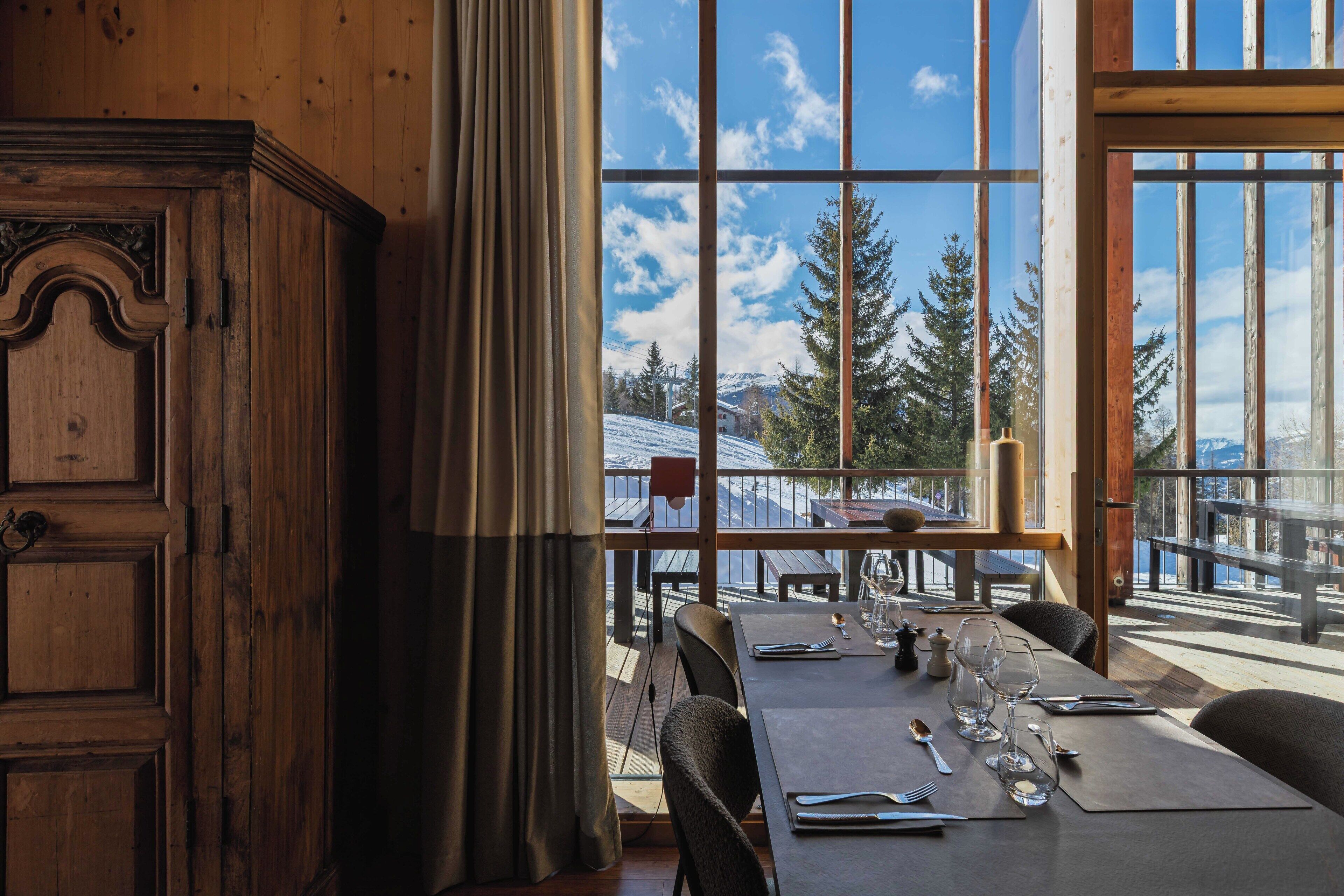 Un comedor con un amplio ventanal con vistas a un paisaje montañoso nevado.