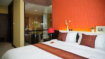 Een hotelkamer met een groot bed, een glazen scheidingswand en een rode accentmuur.