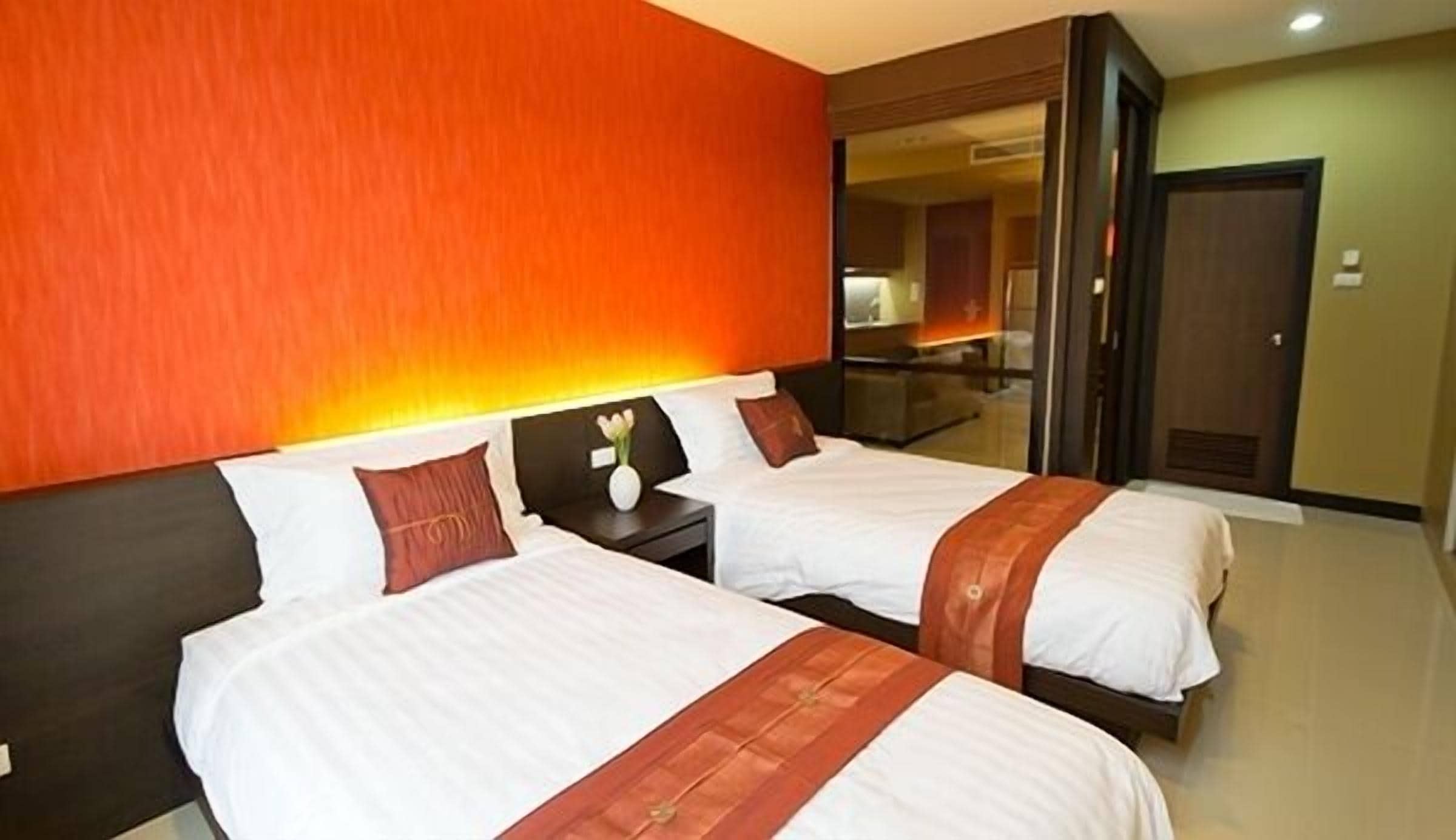 Una habitación de hotel con dos camas, una mesita de noche y un espejo.