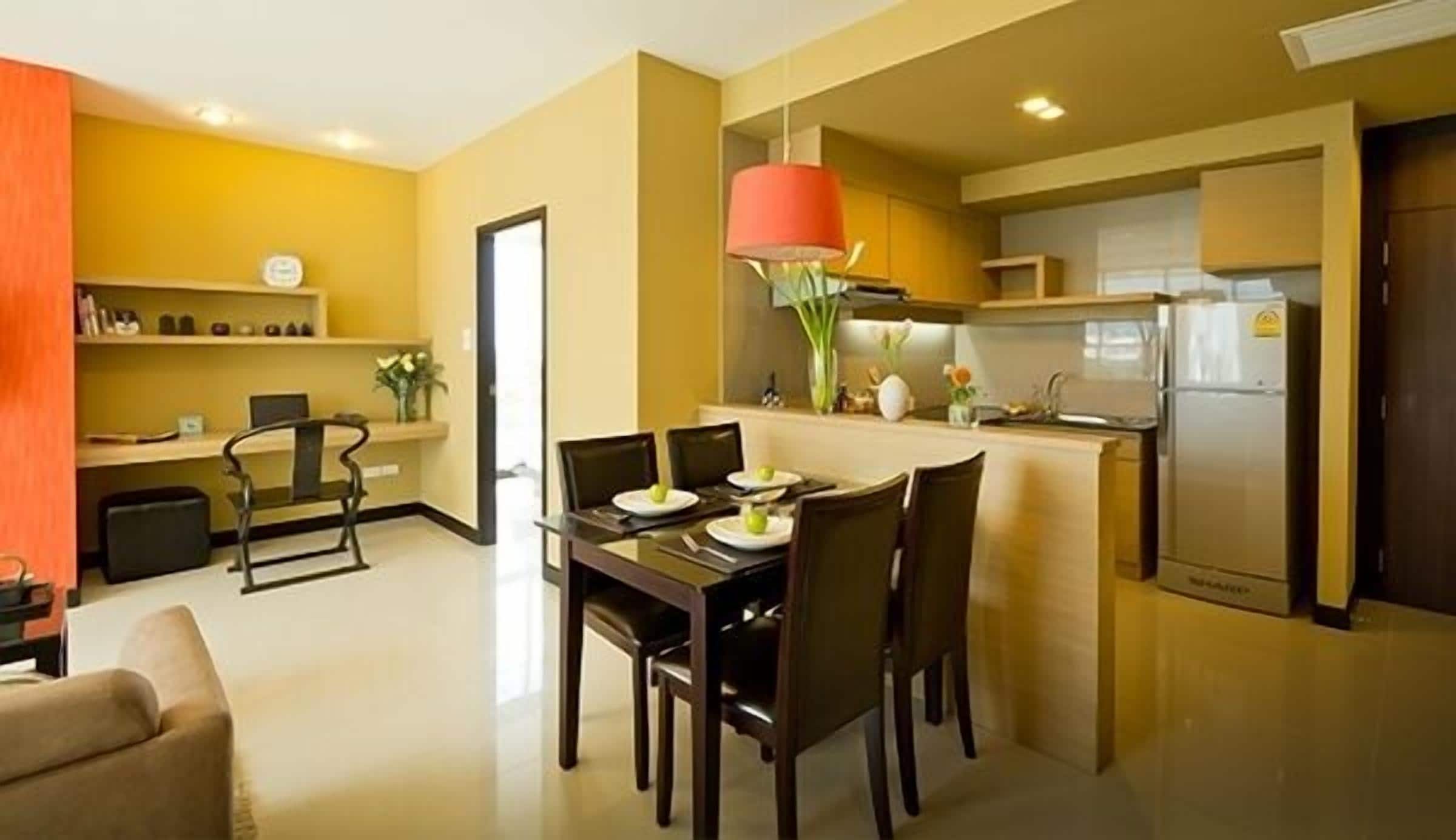 Une cuisine moderne dotée d’un îlot central, un coin repas avec une table et des chaises, et un espace salon avec un canapé.