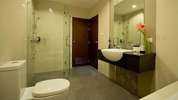 Un baño moderno con cabina de ducha de vidrio, inodoro blanco, tocador doble y un espejo grande.