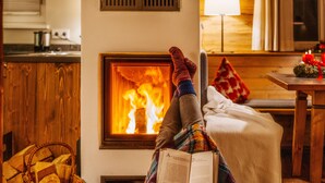 A cozy room with a fireplace, a comfortable couch, and a basket of firewood. - Torfhaus HARZRESORT (Clausthal-Zellerfeld)