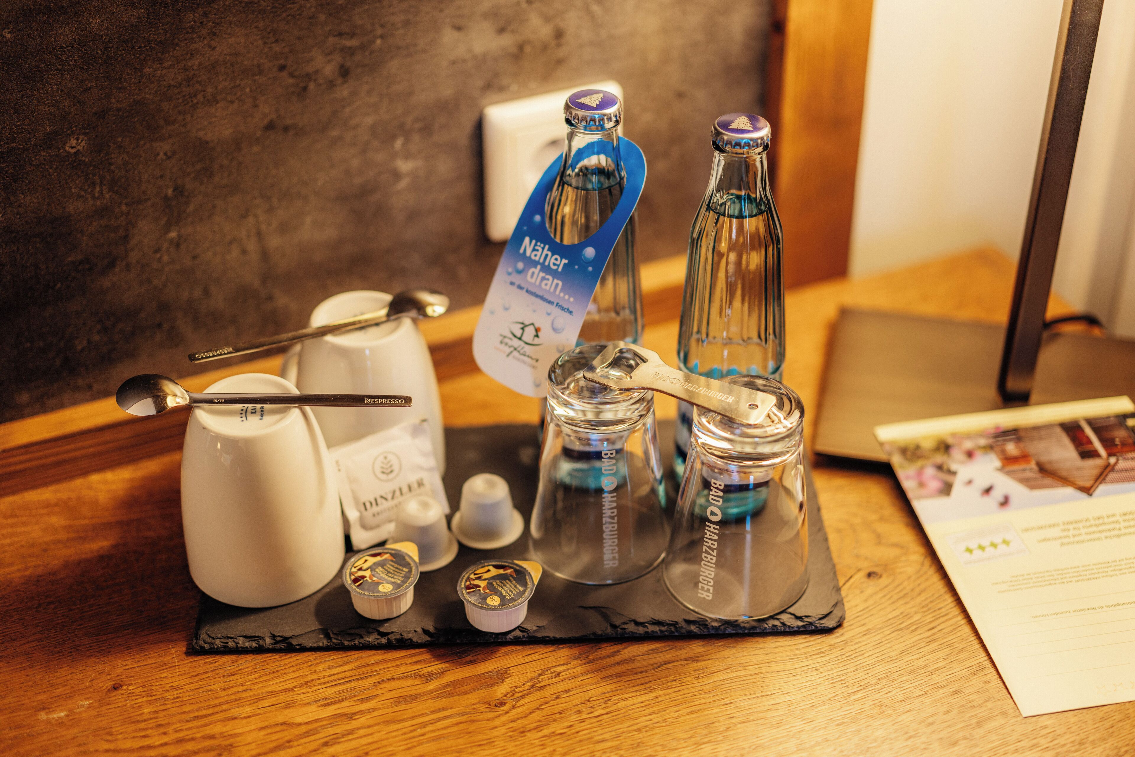 A table with a coffee maker, a spoon, a card, and two bottles labeled "Bado Hartburger".