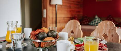Un desayuno con una mesa para dos, que incluye un bol de frutas, una taza y un vaso de zumo de naranja.