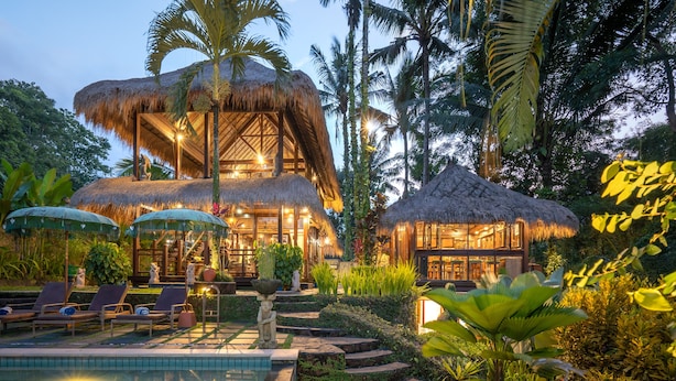 A resort with a pool, thatched-roof structures, and lush tropical vegetation. - Villa Kupu-Kupu (Ubud)