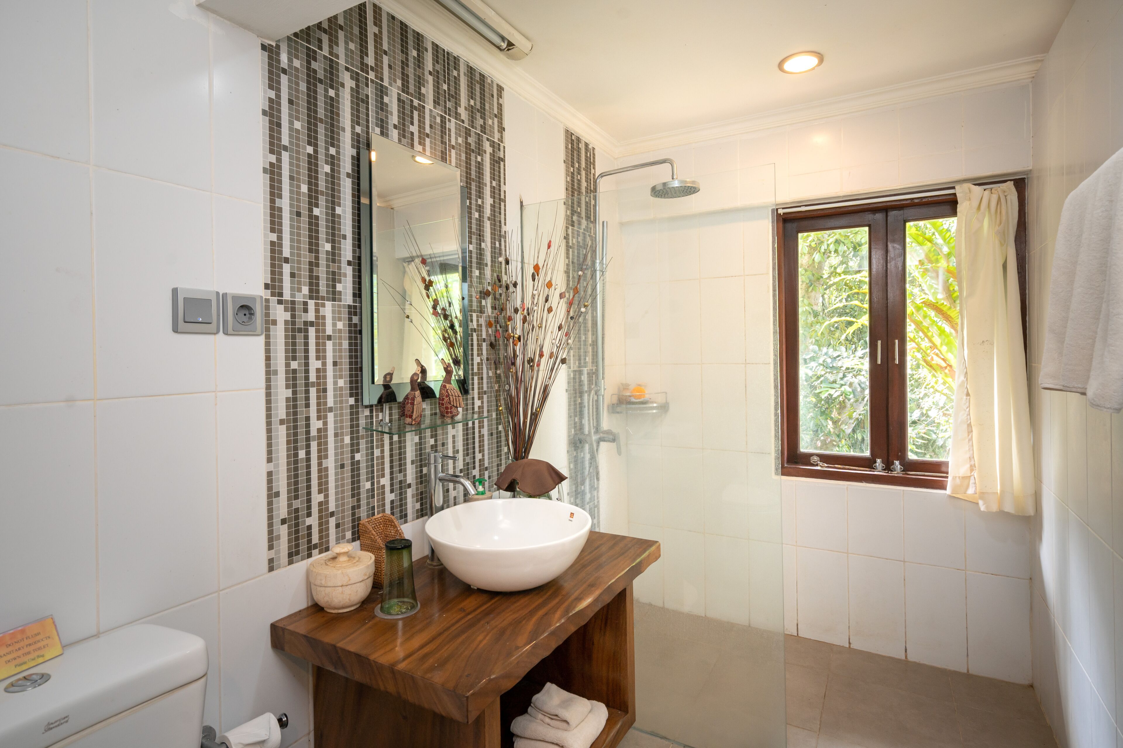A bathroom with a large mirror, a wooden vanity, a white sink, and a shower.