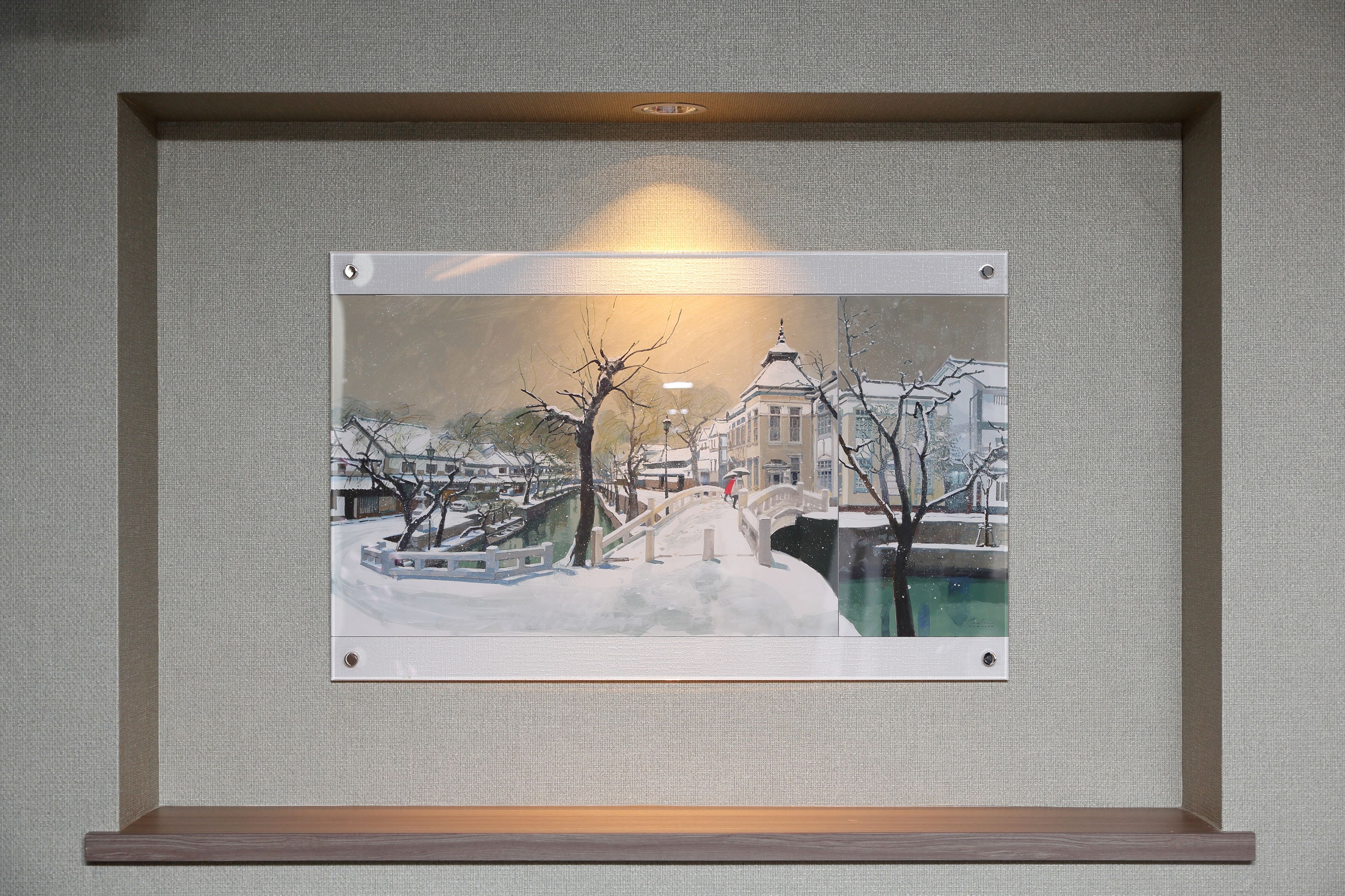 Une œuvre d’art encadrée représentant un paysage enneigé avec un pont et des bâtiments.